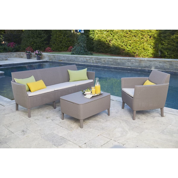 Háromszemélyes, szürke műrattan kerti kanapé, világos párnákkal, mellette egy fotellel és asztallal, egy medence mellett elhelyezve, napfényes kertben. Az összes bútor időjárásálló és könnyen tisztítható.