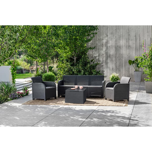 5 személyes ROSALIE műrattan kertibútor szett zöld környezetben, lekerekített kartámaszokkal, párnatartós asztallal. A szetthez tartozó kanapék és székek kényelmes ülései polipamut párnákkal vannak ellátva, kültéri használatra