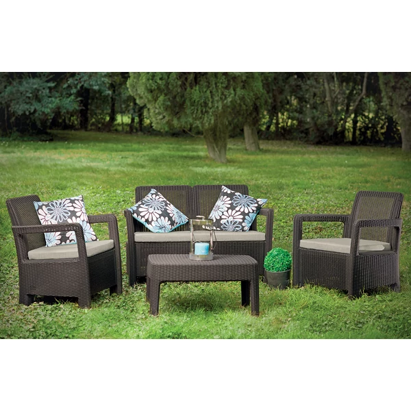 Kerti bútor szett, két fotellel, egy kétszemélyes kanapéval és négyszögletes asztallal, rattan imitáló felülettel. A bútorok szürke párnákkal díszítettek, zöld fű háttérrel, ideális családi összejövetelekhez.