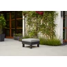 Moduláris ELEMENTS asztal párnával, szürke textilbőr ülőpárnával, fekete alumínium vázzal. Kertben elhelyezve, zöld növények és virágok között, időjárásálló és UV-védett kialakítással.