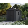 Új, modern stílusú NEWTON 2.0 9 x 7,5 műanyag kerti ház, sötét színben, szabályozható ablakokkal, zöld környezetben, kövezett ösvény mellett elhelyezve, ideális tárolásra és kertészkedésre.